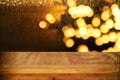 wood board table in front of Christmas warm gold garland lights on wooden rustic background Royalty Free Stock Photo