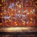 Wood board table in front of Christmas warm gold garland lights on wooden rustic background. filtered image. selective focus Royalty Free Stock Photo