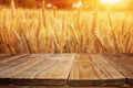Wood board table in front of field of wheat on sunset light. Ready for product display montage
