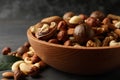 Wood bowl with different tasty nuts on gray wooden background Royalty Free Stock Photo