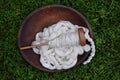 Wood bowl filled with white cotton roving and a spindle and a bobbin on a green grass background