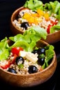 Wood bowl with spelt salad with olives and tomatoes