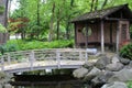 A wood bridge crossing a stream leading to a small pavilion in a Japanese Garden filled with ferns and trees in Wisconsin