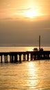 Wood bridge with sunrise behind. Idyllic view of the long pier with wooden bench on the sea. Sunset or sunrise over the water Royalty Free Stock Photo