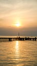 Wood bridge with sunrise behind. Idyllic view of the long pier with wooden bench on the sea. Sunset or sunrise over the water Royalty Free Stock Photo