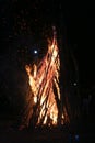 Wood burning at night. Campfire at touristic camp in mountains. Flame and fire spark on dark abstract background. Hellish fire