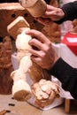 Wood carver's hands sculpting a wooden angel in workshop