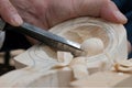 Wood carving. Close-up. A sharp cutter removes chips in a wooden block. Traditional manufacture of a spoon in a manual way.