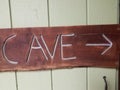 wood cave sign on door with arrow