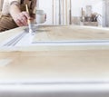 Wood crafts, close up hands woman artisan carpenter painting with brush and paint jar white the door in workshop, wearing overall