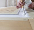 Wood crafts, close up hands woman artisan carpenter painting with brush and paint jar white the door in workshop, wearing overall