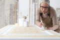 Wood crafts, woman artisan carpenter painting with brush and paint jar white the door in workshop, wearing overall and eyeglasses