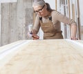 Wood crafts, woman artisan carpenter painting with spray gun paint white the door in her workshop, wearing overall and eyeglasses