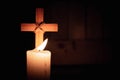 Wood cross by candlelight. Light of faith is shining in darkness of unbelief. Concept of Christianity, religiosity and sincere