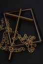 See brown wood & gold Christian cross on diagonal surrounding scattered gold broken chain & empty picture frame on black backgroun Royalty Free Stock Photo