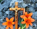 Crucifix in front of rock with orange flowers