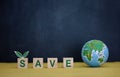 Wood cube block with SAVE word and globe model on dark blue background Royalty Free Stock Photo