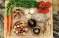 Wood cutting board in kitchen table with fresh ingredients carrot, mushroom, potatoes, tomatoes, food many colors orange, red. Royalty Free Stock Photo