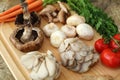 Wood cutting board in kitchen table with fresh ingredients carrot, mushroom, potatoes, tomatoes, food many colors orange, red. Royalty Free Stock Photo