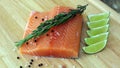 Wood cutting board in kitchen table with fresh red salmon fish salt pepper and lime ready to cook. Royalty Free Stock Photo