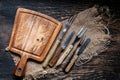 Wood cutting board with a piece of burlap, knives and forks on wooden table with copy space, top view