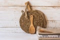 Wood cutting board, rattan coaster, spoon, stack of linen towels on wood table, mockup, styled image