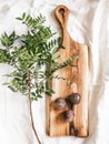 Wood cutting board, ripe figs and green branch on white tablecloth. top view Royalty Free Stock Photo