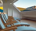 Wood deck lounge chairs at sunrise, stern verandah of cruise ship, Skagway, AK. Royalty Free Stock Photo