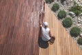 Wood deck renovation treatment, the person applying protective wood oil with a brush on ipe terrace