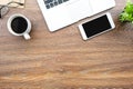 Wood desk table with smartphone with blank mock up screen, laptop computer and up of coffee with sun light in the morning. Top Royalty Free Stock Photo