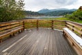 A large wood patio by a lake with mountains in the background