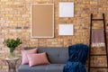 Wood empty frames with copy space and plant against brick wall in room with couch Royalty Free Stock Photo