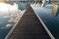 Wood empty pier to the sea at marina at sunrise with clouds in reflection. Travel and vacation concept