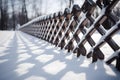 Wood fencing covered with snow in winter illuminated by the morning sun. Royalty Free Stock Photo