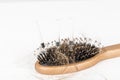 Wood hairbrush on white background. Close-up with long brown hair and syringe to illustrate hair loss treatment medicine