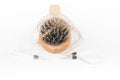 Wood hairbrush on white background. Close-up with long brown hair and syringe to illustrate hair loss treatment medicine