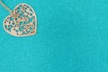 Wood heart on bright teal glitter background