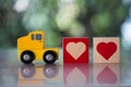 Wood heart follow yellow toy car for sending to couple. The concept of love