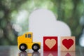 Wood heart follow yellow toy car for sending to couple. The concept of love