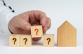 On a white surface there is a model of a house, next to it a man has placed cubes with the inscription - question mark Royalty Free Stock Photo