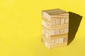 Wood jenga game with wooden block Stack tower on yellow background, manage risk and strategy Royalty Free Stock Photo