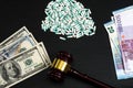 Wood judge& x27;s gavel and scattered colorful drugs on the dollar an Royalty Free Stock Photo