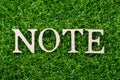 Wood letter in word note on green grass background