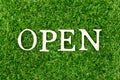 Wood letter in word open on green grass background
