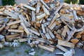 Wood is lying in a pile near the fence. Wooden logs prepared for kindling the stove in winter