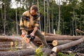 Wood man in protective goggles sawing with chainsaw tree trunk in summer forest. Royalty Free Stock Photo