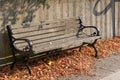 Wood and metal park bench along a sunny sidewalk and modern stone retaining wall Royalty Free Stock Photo