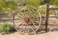 An old wagon wheel leaning against a wooden fence in the desert Royalty Free Stock Photo