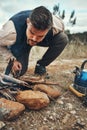 Wood, nature and man with fire on a camp on a mountain for adventure, weekend trip or vacation. Stone, sticks and young Royalty Free Stock Photo