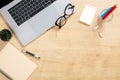 Wood office desk table with laptop computer, glasses, paper notepad, pen, stationery. Minimal flat lay style composition with copy Royalty Free Stock Photo